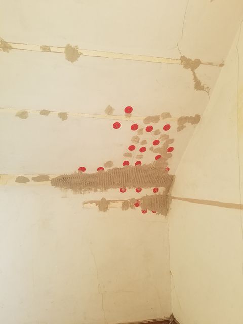 Corner of a room with beige walls and a textured ceiling.