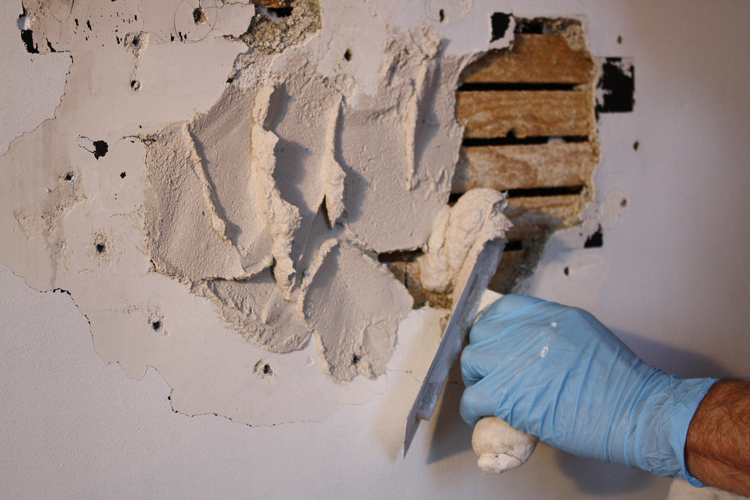 “Applying fresh plaster over damaged wall section to repair exposed lath.