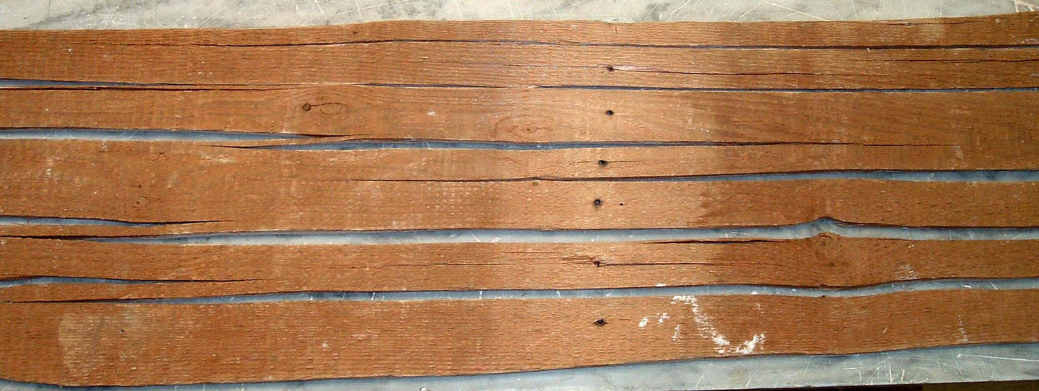 Stack of wooden planks with visible grain and texture on a gray surface