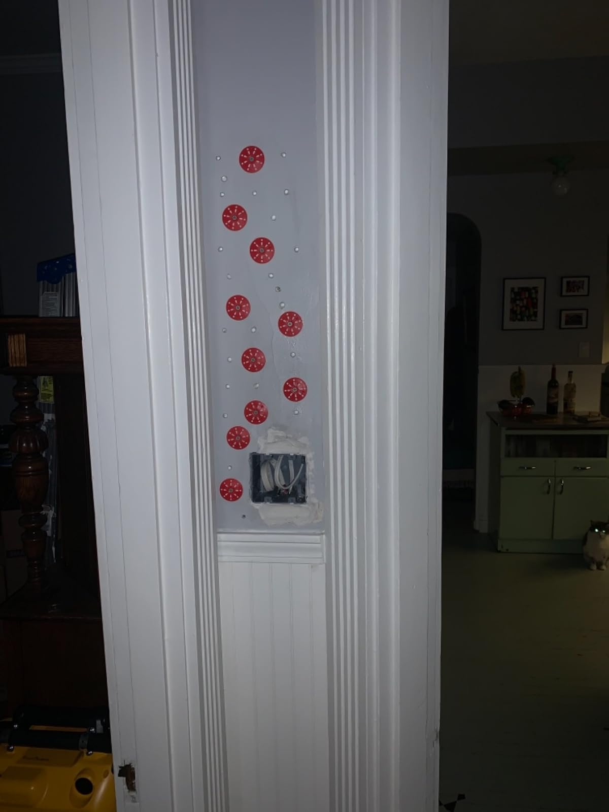 Plaster wall beside doorway marked with red adhesive injection points for reattachment