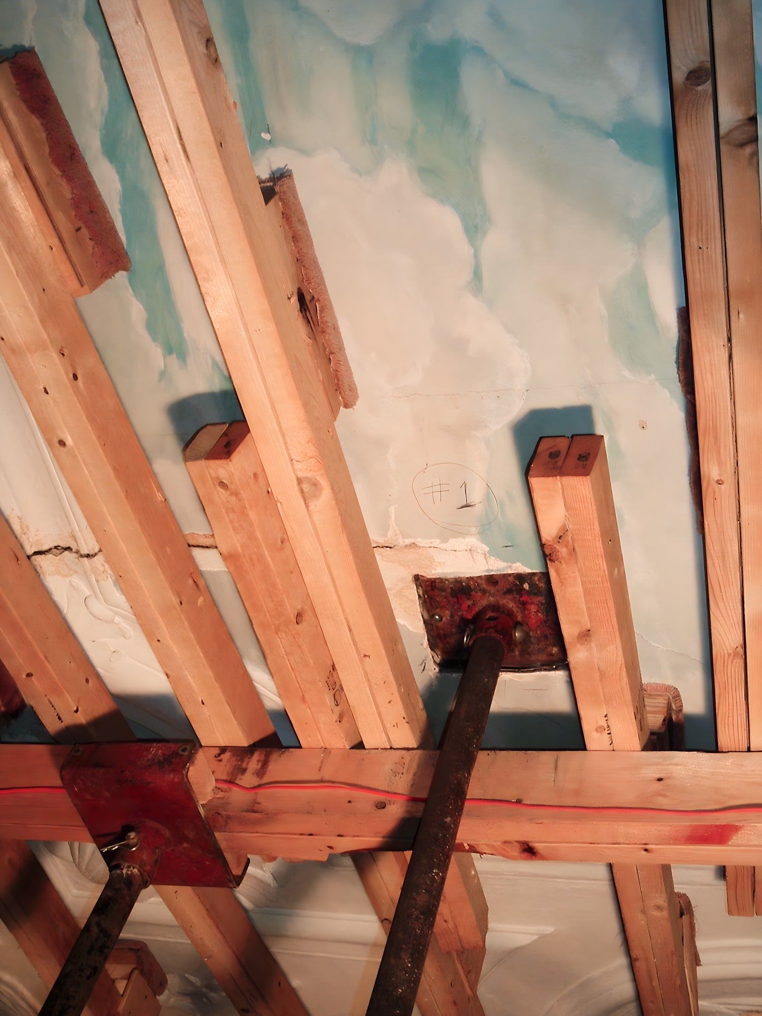 Wooden beams and a ladder against a wall with peeling paint