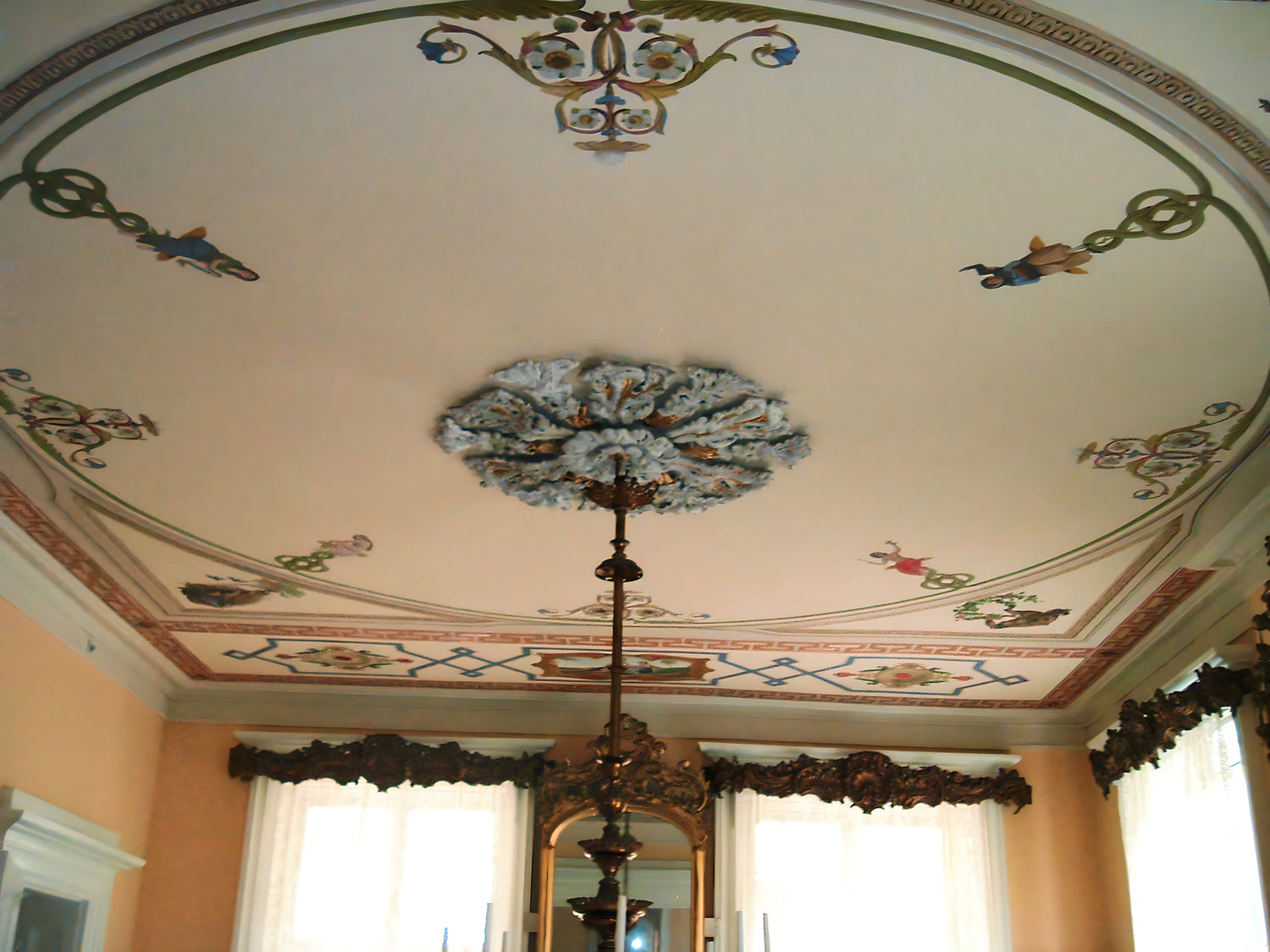 Decorative ceiling with intricate patterns and a chandelier in a room.