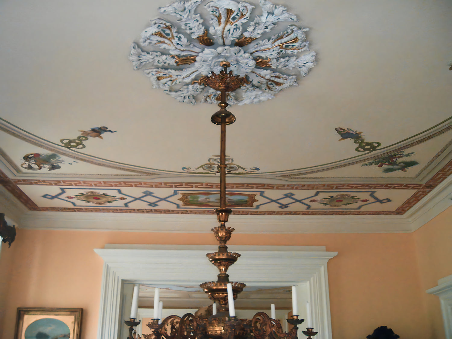 Decorative chandelier hanging from a ceiling with decorative molding and a mirror in the background.