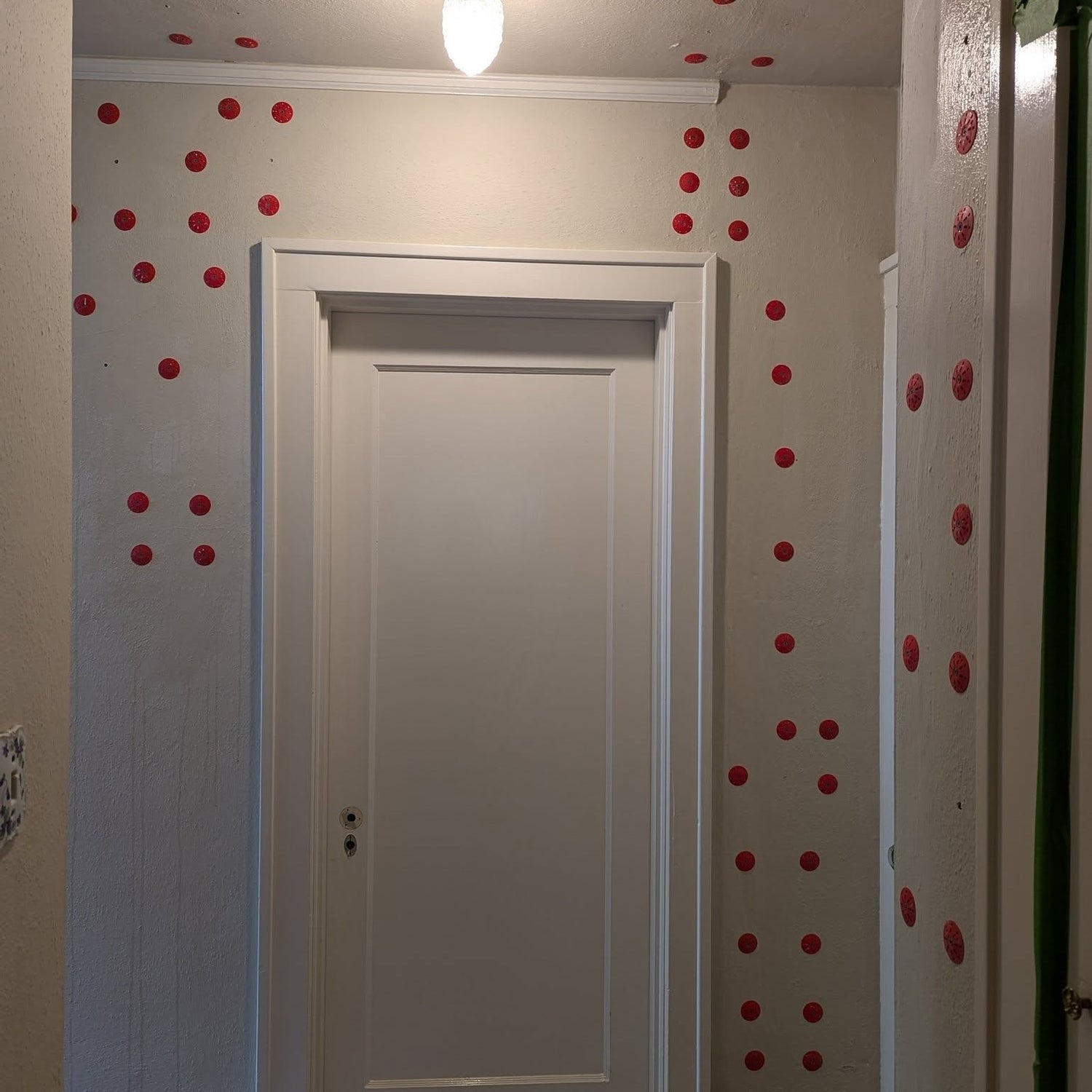 Plaster walls around a door frame marked with red adhesive injection points during reattachment work