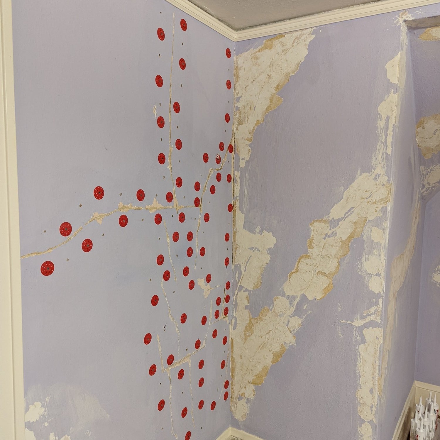 Wall showing plaster detachment with red adhesive injection points marked for reattachment