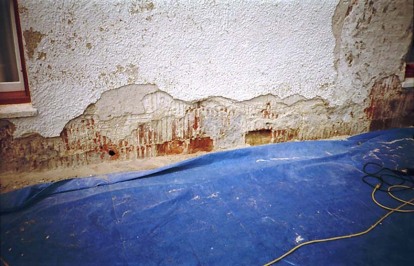 Wet wall with water damage and blue tarp on the floor

