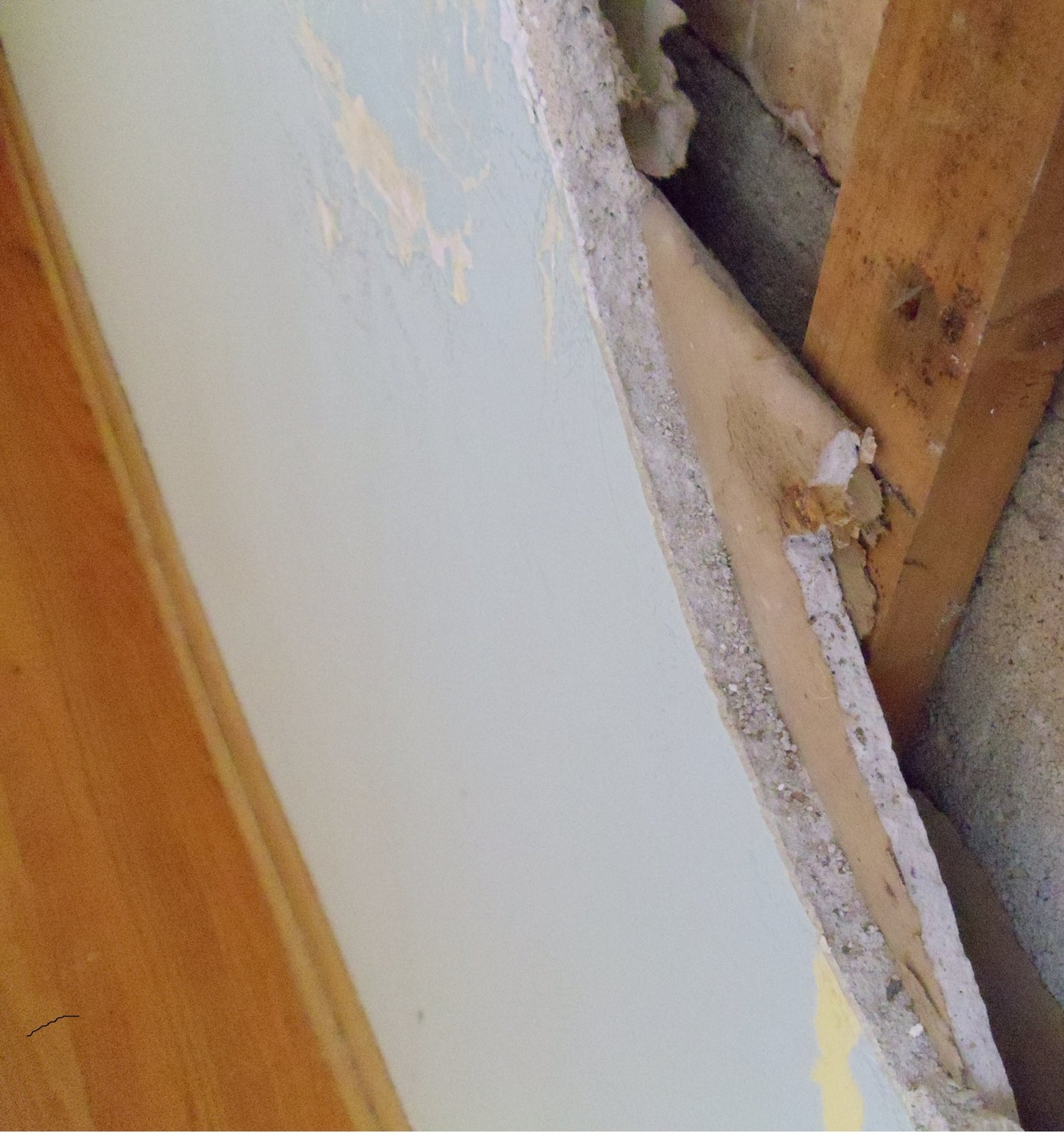 Close-up of a wall with drywall damage and exposed insulation.