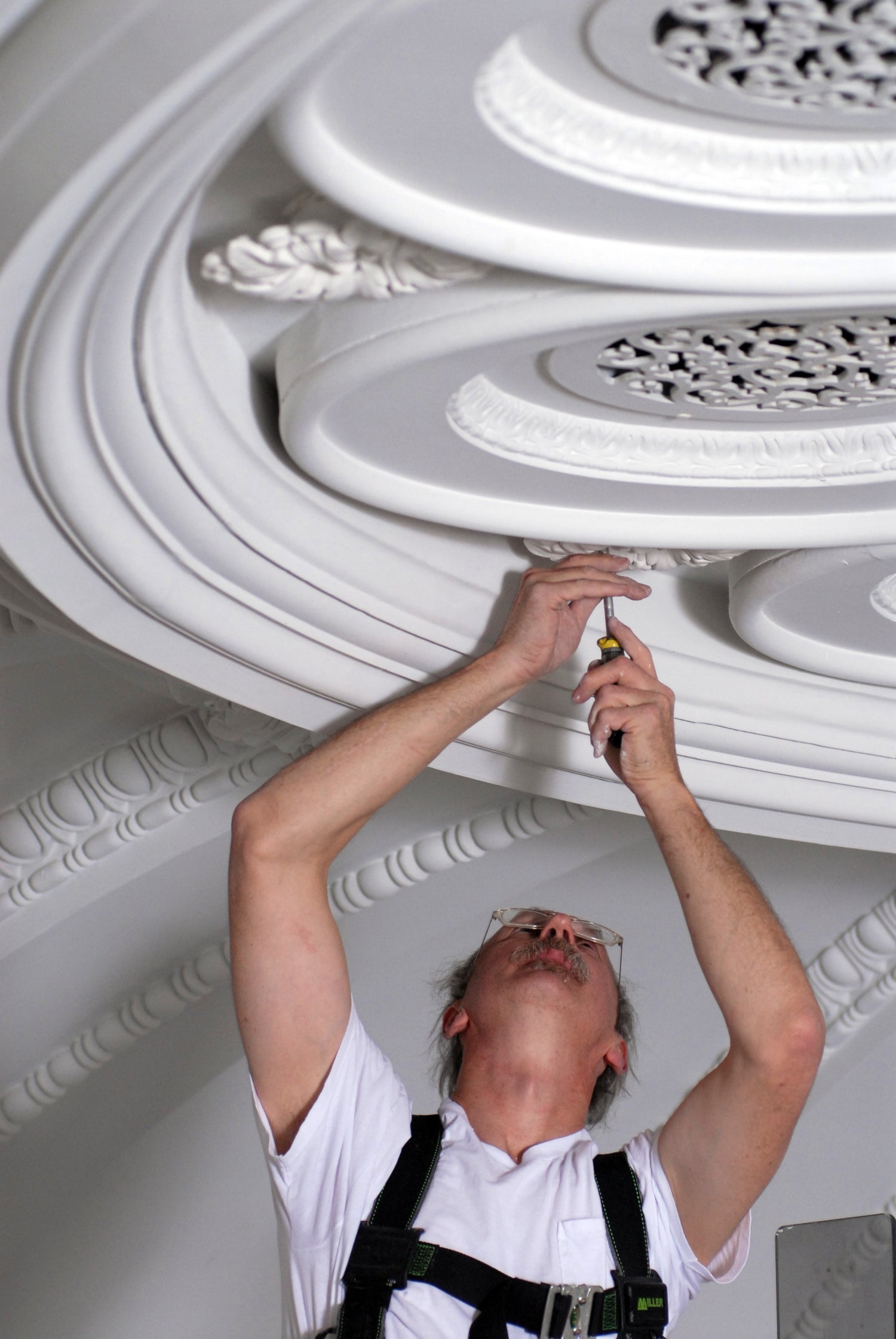 Person installing ornate ceiling molding