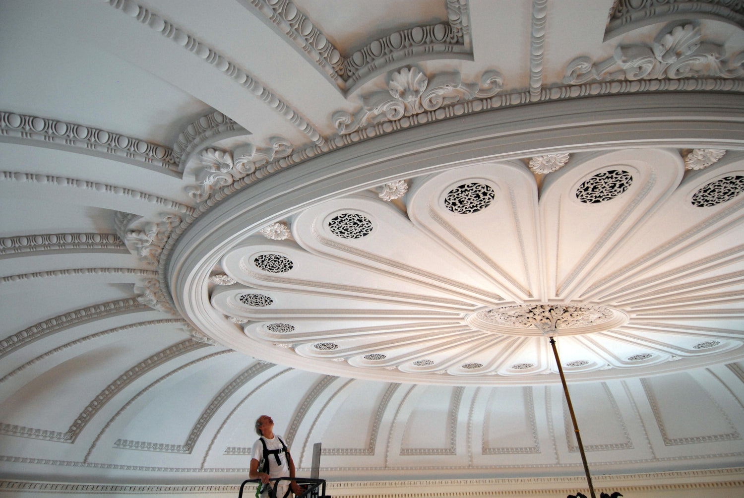 Man walking under a large ornate ceiling with decorative patterns