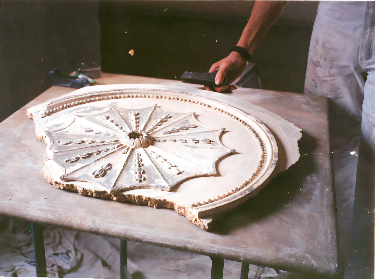 Decorative stone panel on a table with a person holding a tool in the background