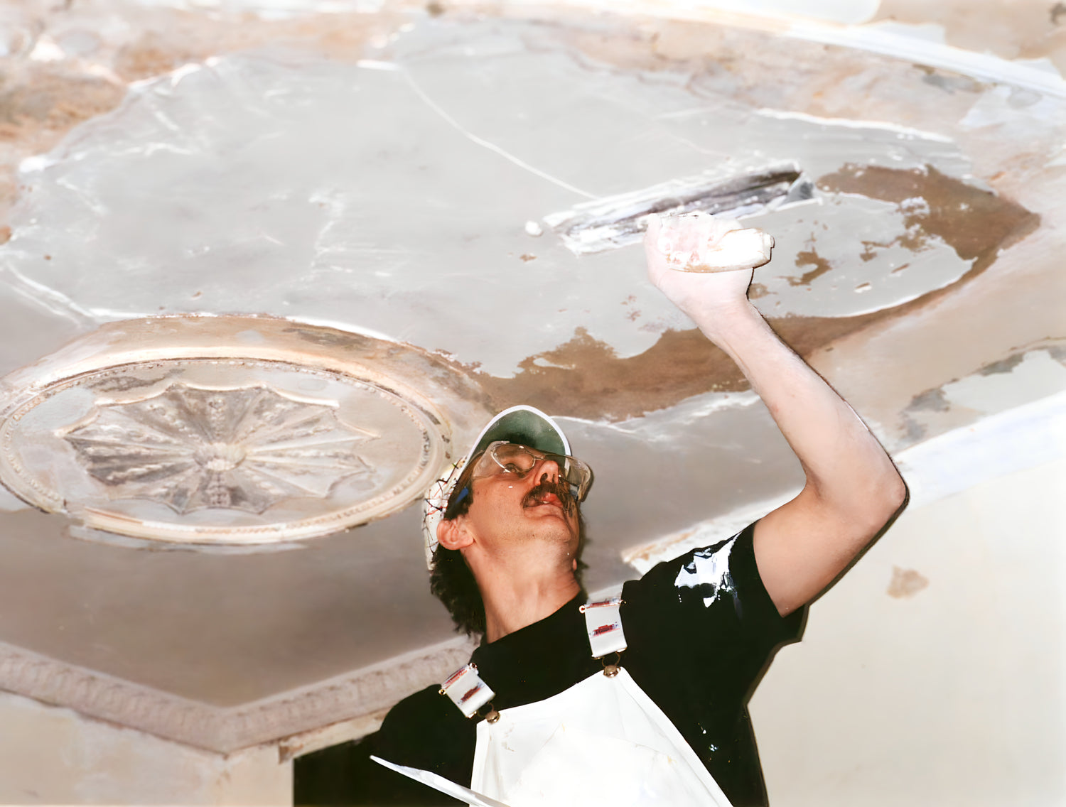 Person applying plaster to a ceiling with a trowel
