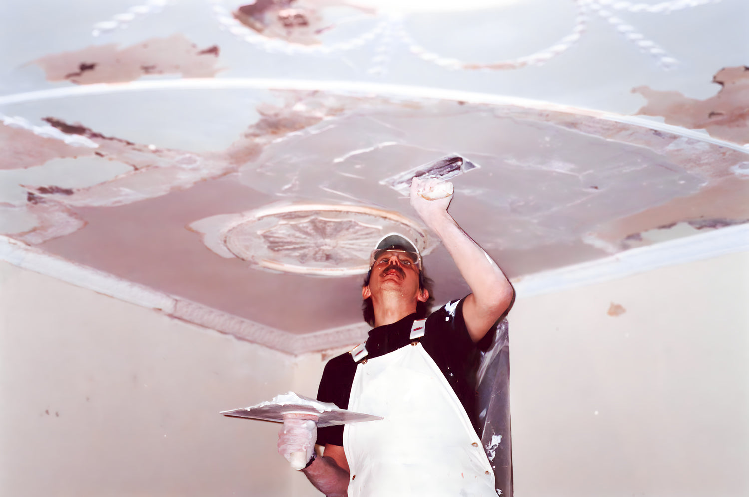 Person applying a white substance to a ceiling
