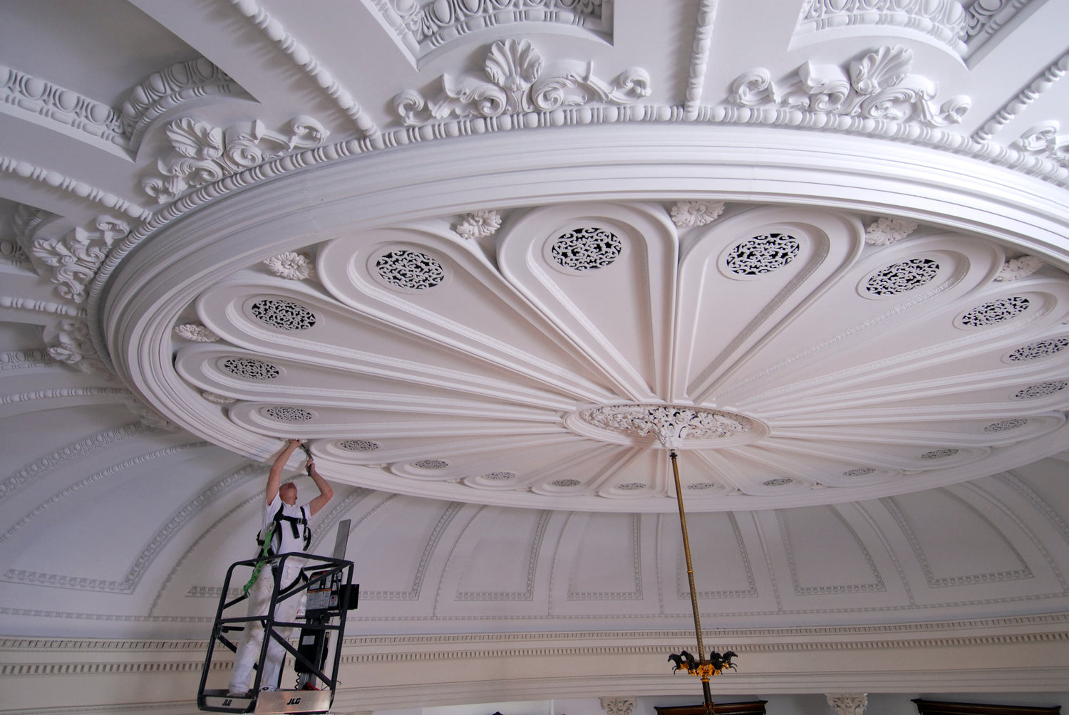 Person on a ladder working on an ornate ceiling