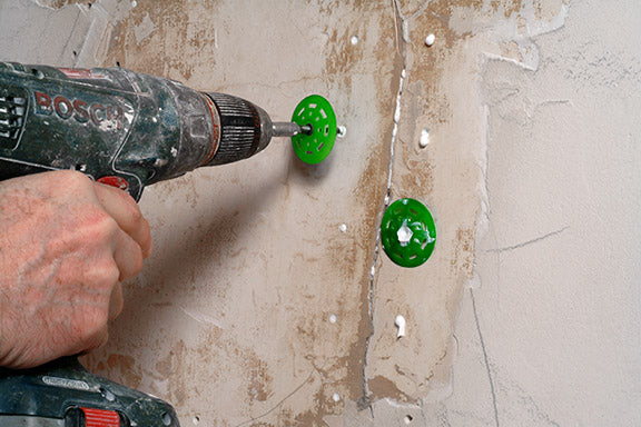 Person using a Bosch drill to create holes in a tiled wall.