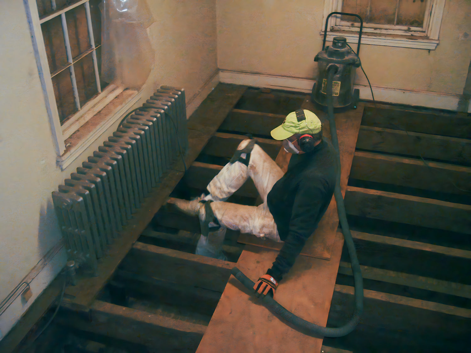 Person using a vacuum cleaner on a staircase in a room with a radiator and window.