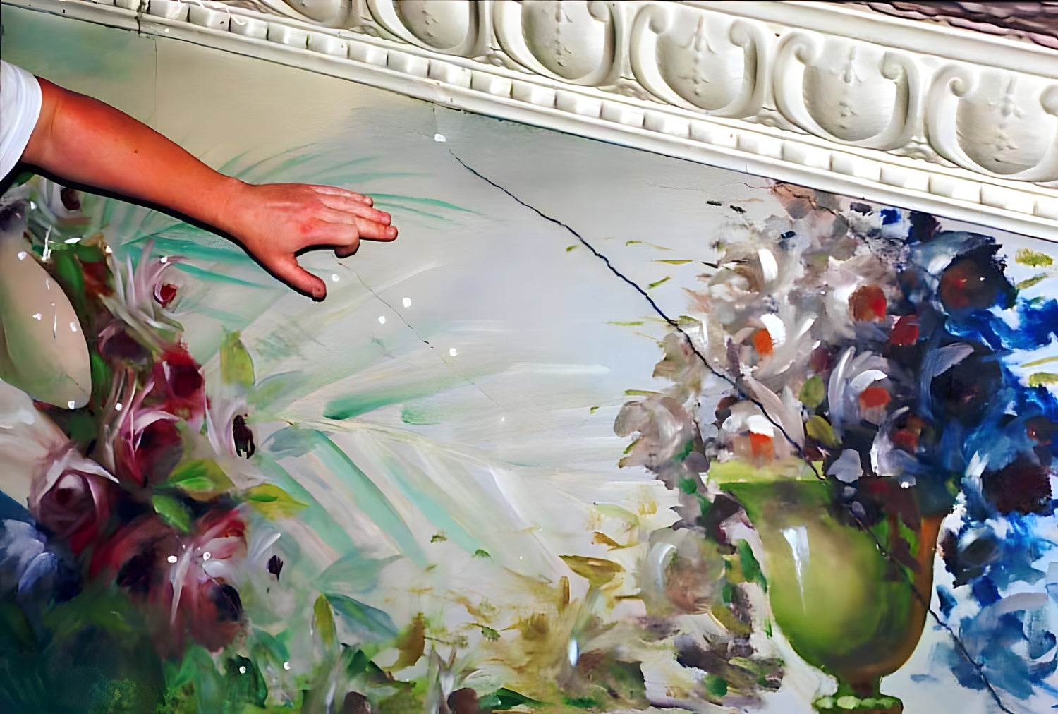 Hand touching a floral painting on a textured surface