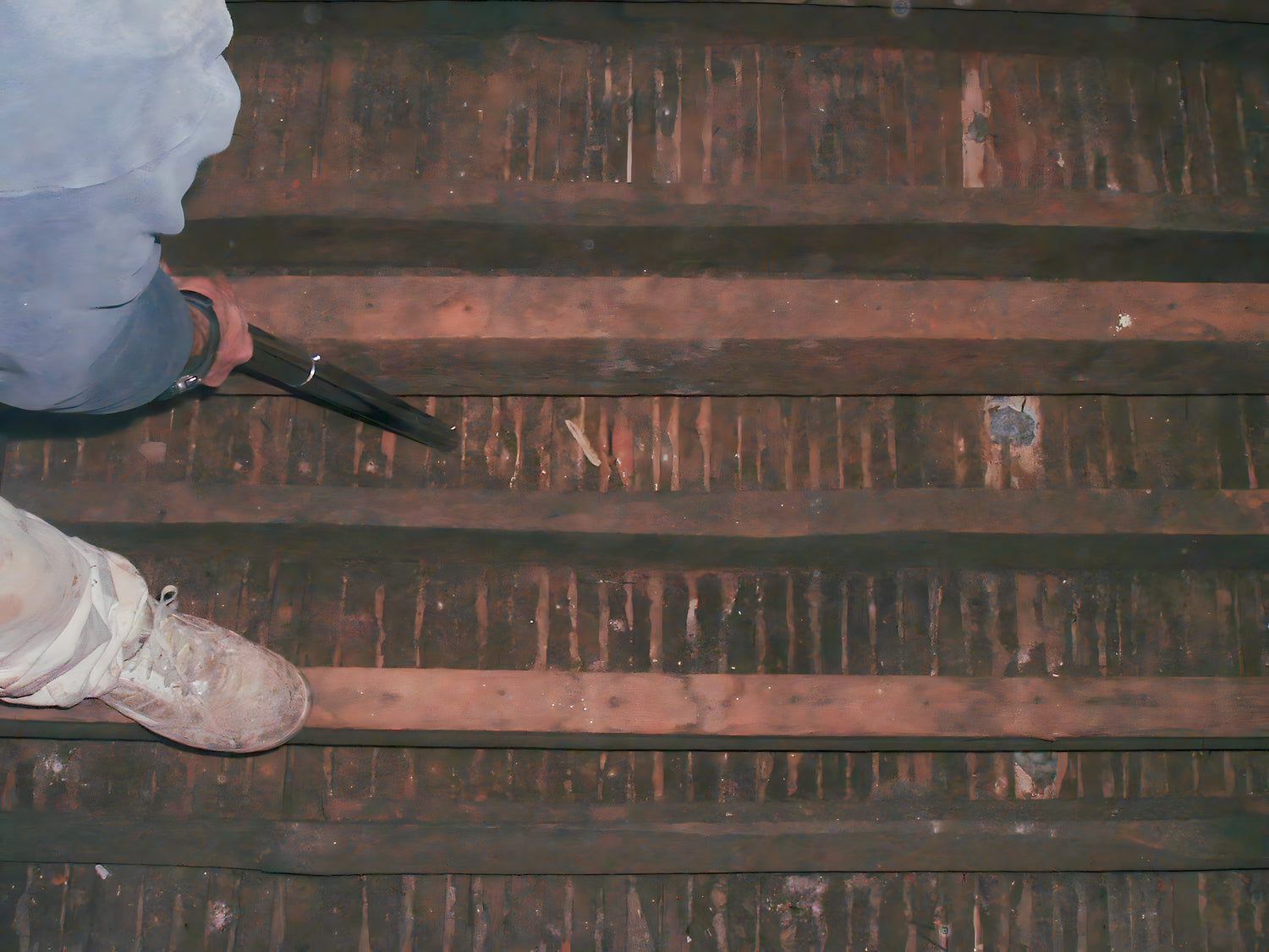 Person standing on a rusted metal surface with a tool