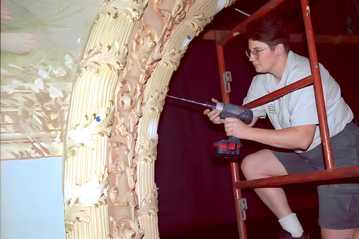 Person using a power drill on a large decorative mirror