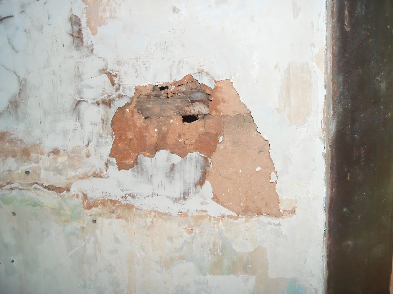 Damaged wall with peeling paint and a large hole
