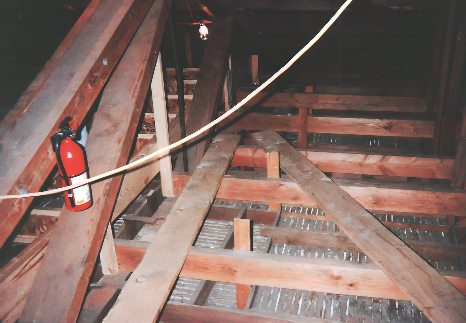 Attic with wooden beams and a fire extinguisher mounted on one of them.
