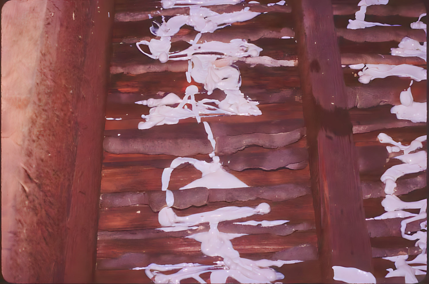 Close-up of wooden beams with white paint flaking off, showing signs of wear.